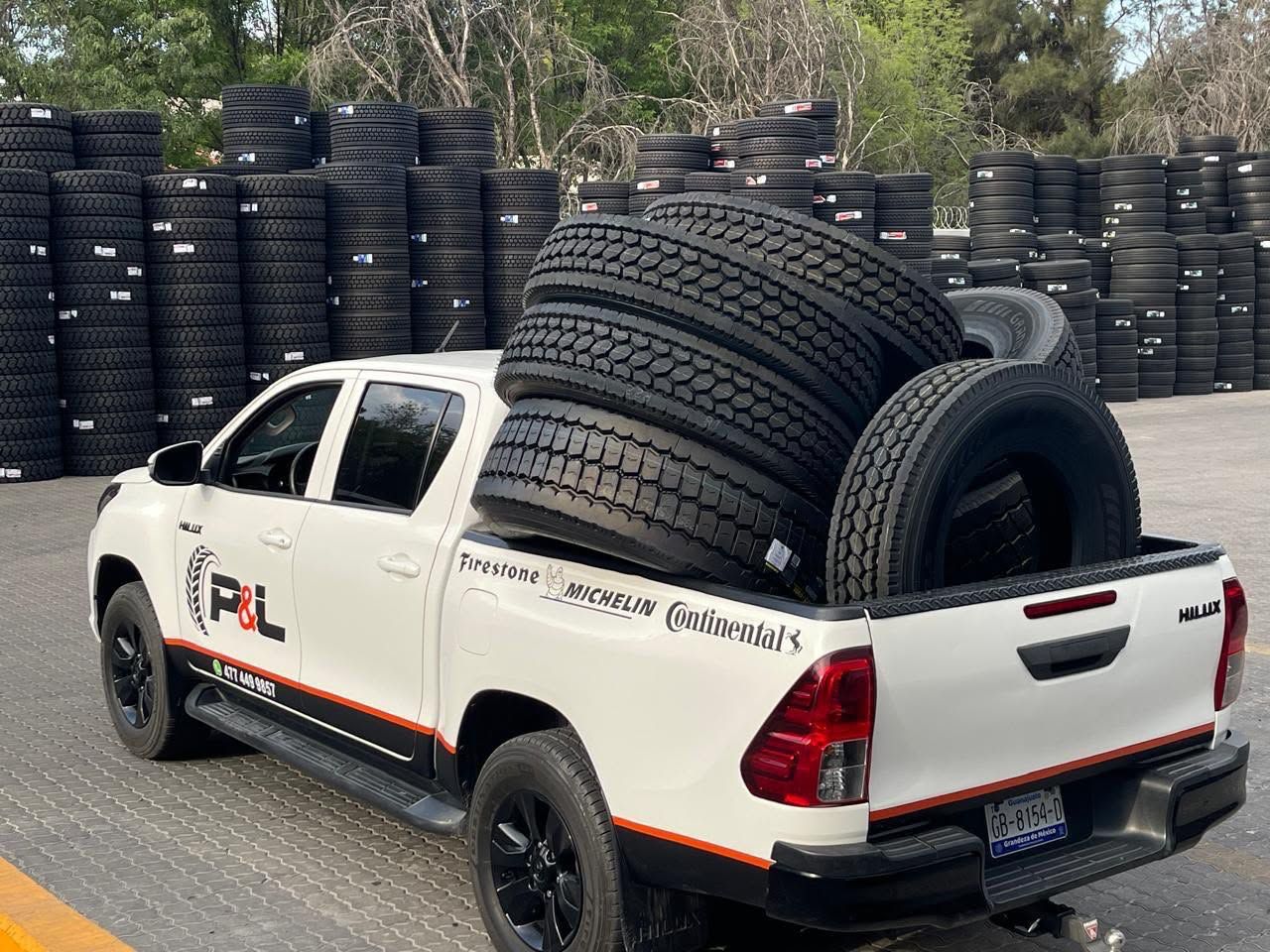 Camioneta de P&L cargada con llantas de camión frente a su inventario de llantas